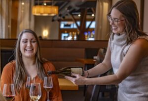 Smiling staff pouring wine for guests in a tasting room