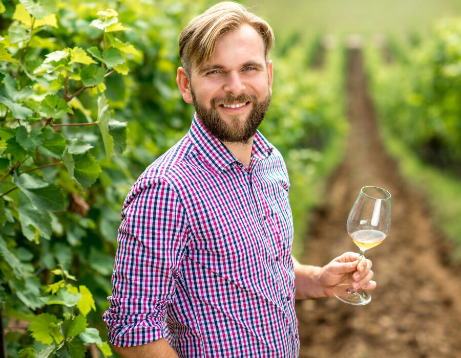 Winemaker holding a glass of white wine in a vineyard