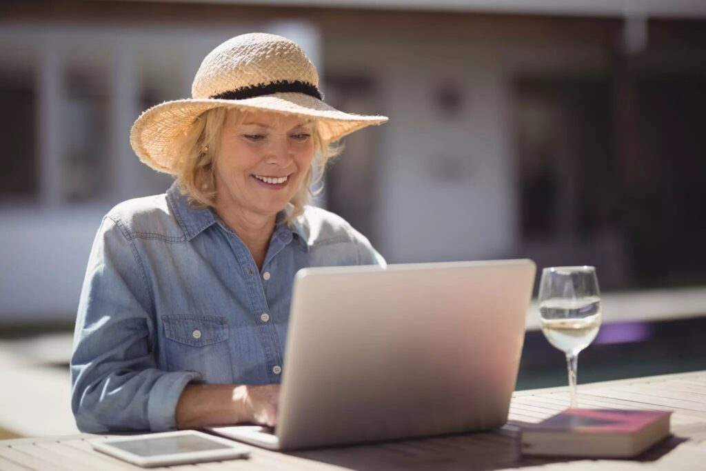 Woman in a sun hat browsing a winery site with a glass of wine